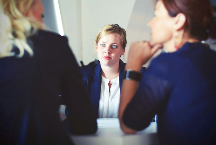 Three professionals in a meeting discussing jobs that people once respected but realized are done by awful people.