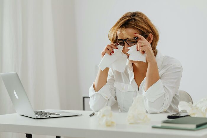 Frustrated woman at laptop crying and holding tissues, representing stories about bosses being out of touch.